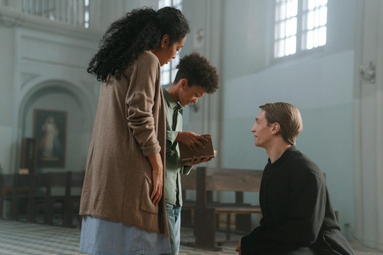 A family shares a moment with a priest inside a church, holding a holy bible.